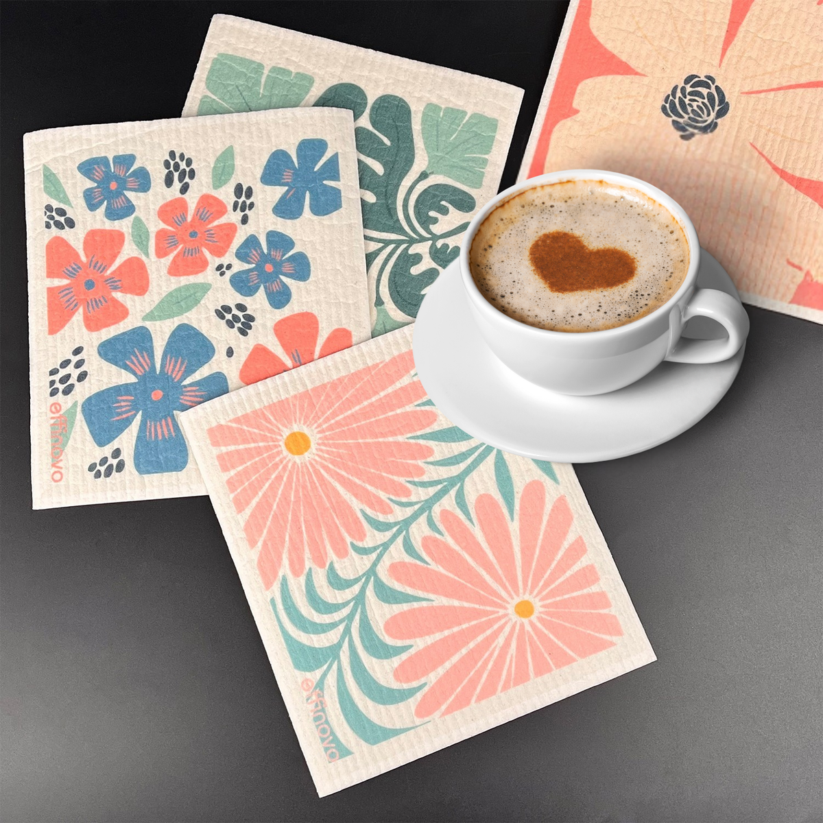Eco-friendly floral sponge cloths with colorful prints next to a cup of coffee on a table